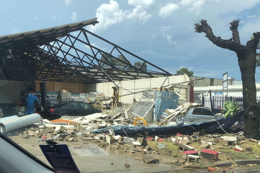 A roof is missing from an industrial building with lots of debris on the ground