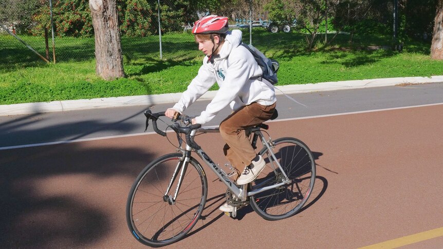 A student in a red helmet on a bike.