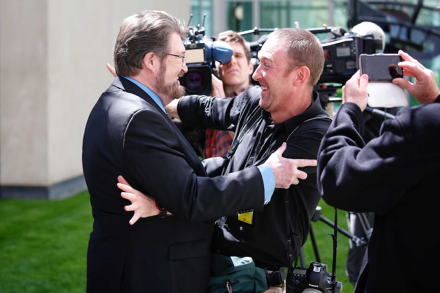 Senator Derryn Hinch embraces Fairfax photographer Andrew Meares on the lawns of Parliament House.