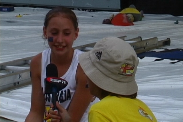 Libby Hall sits on a crash mat and is interviewed by an ESPN reporter.
