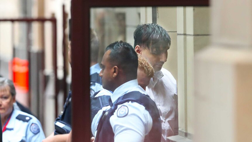 James Gargasoulas in handcuffs, is escorted by police officers.