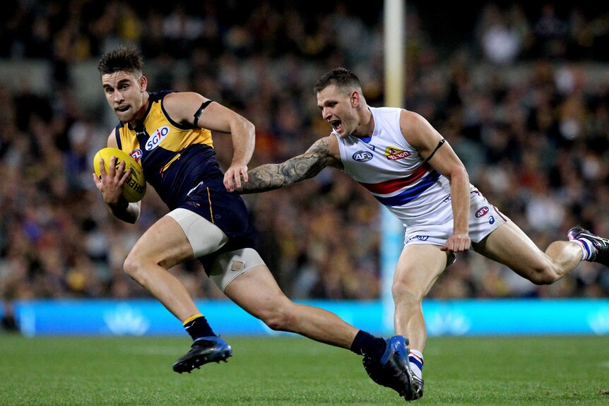 Elliot Yeo of the West Coast Eagles avoids a tackle and runs away from Western Bulldogs player Clay Smith.