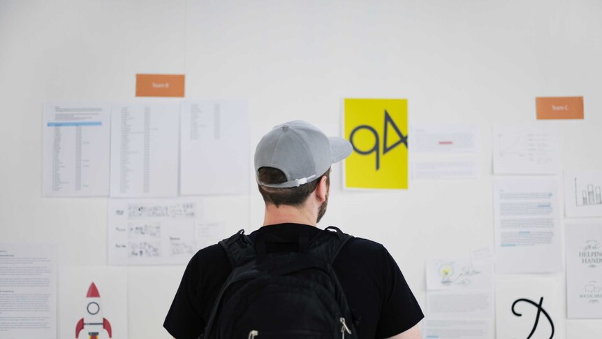 A man faces a wall looking at financial and other information