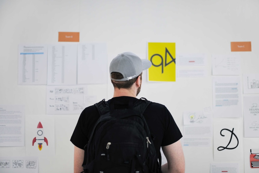 A man faces a wall looking at financial and other information