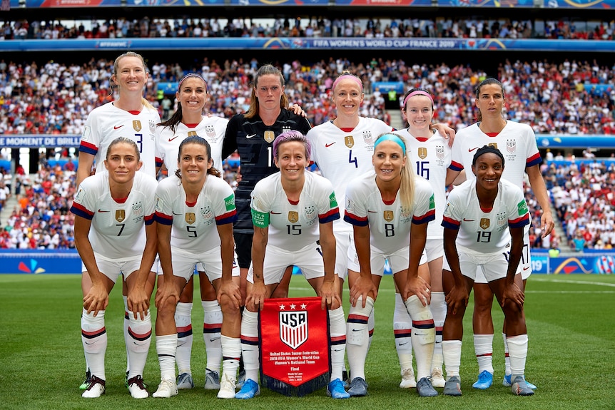 Women soccer players wearing white pose for a photo