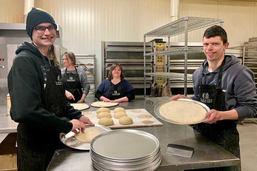Two participants in the Abled Kitchen program holding up their pizza bases. 
