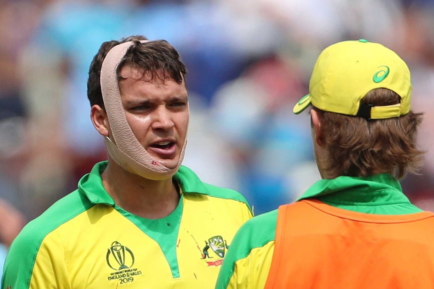 Alex Carey has a blood-stained bandage around his head. There is also blood on his shirt.