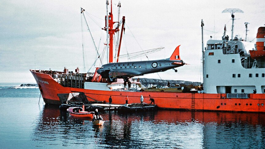 Picture of a plane being unloaded from an orange ship