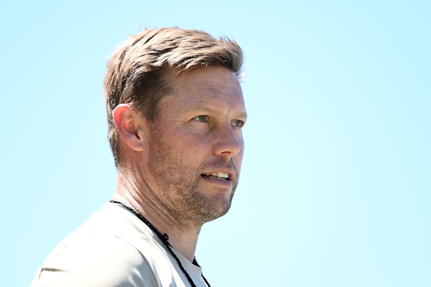 Sam Mitchell looks up with a clear blue sky behind him