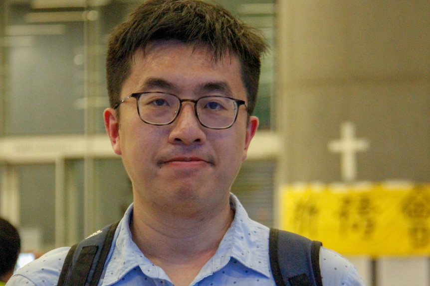 An Asian man in a blue shirt looking serious