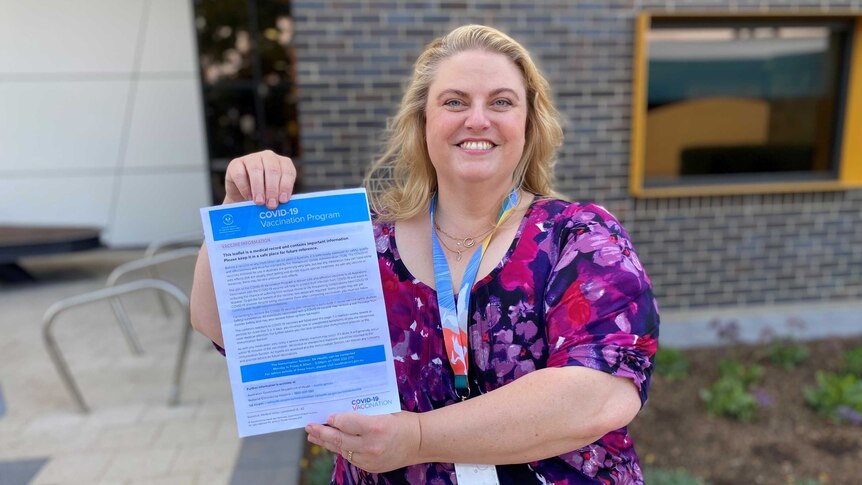 Caroline Phegan holding a certificate in front of a hospital