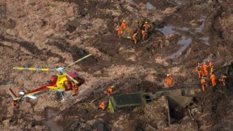 Rescue workers in a field of mud.