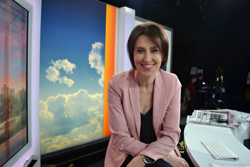 Virginia Trioli smiles as she sits at her presenter's chair on the News Breakfast set.