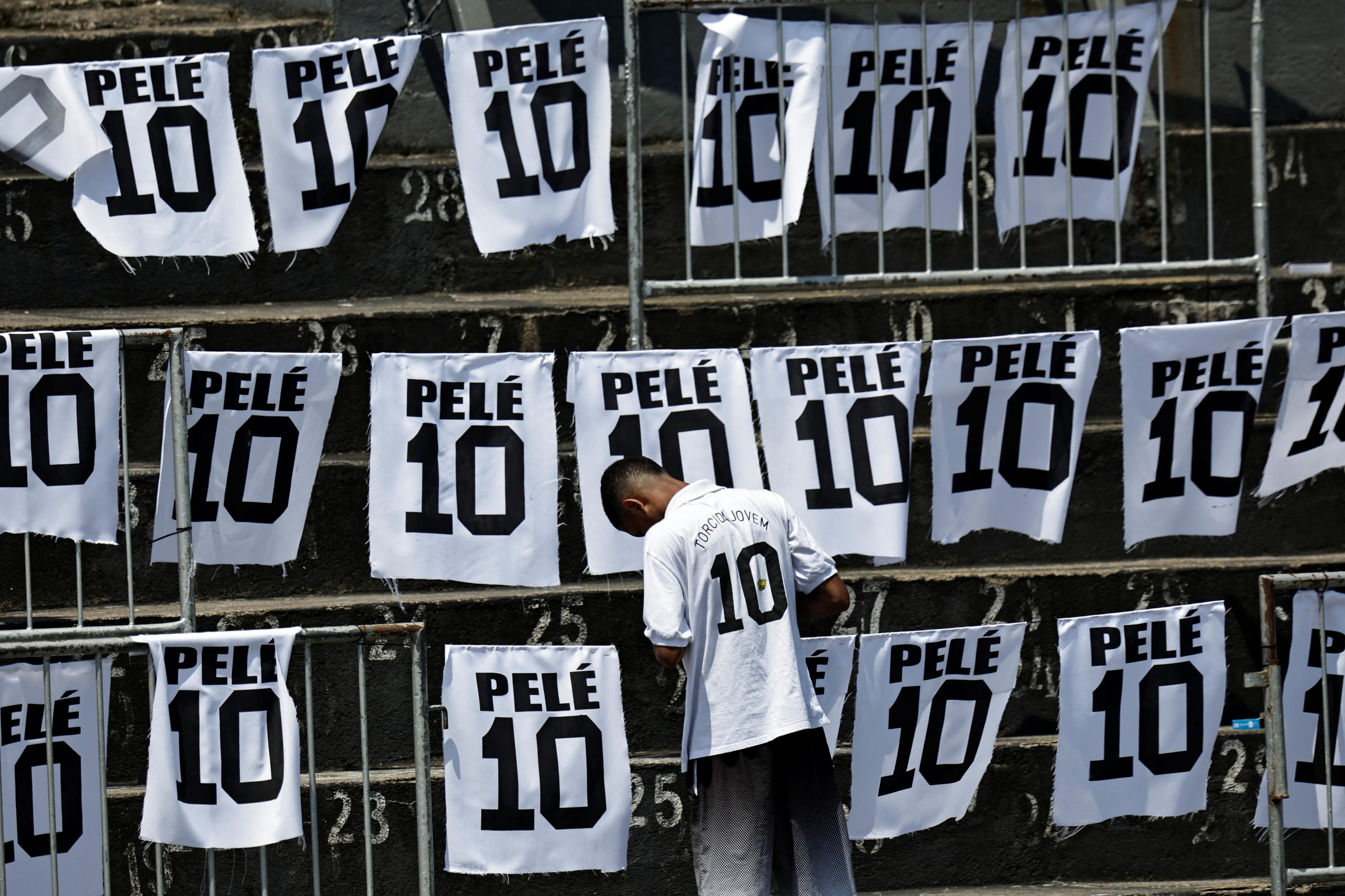 A boy wears a Pele jersey standing in front of pieces of material with Pele written on them and number 10. 
