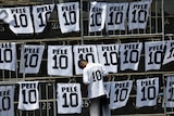 A boy wears a Pelé jersey standing in front of pieces of material with Pele written on them and number 10. 