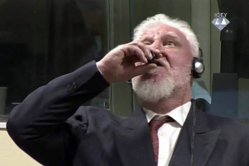 Slobodan Praljak tilts his head and brings a bottle to his lips