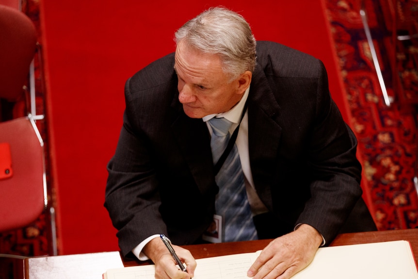 a man sitting at a desk signing a book