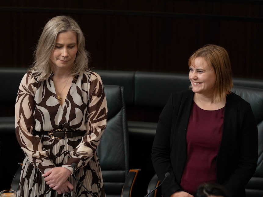 Two female politicians sit in parliament house.