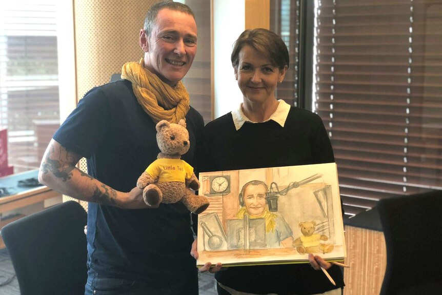 A man and woman and teddy bear with a drawing of the man