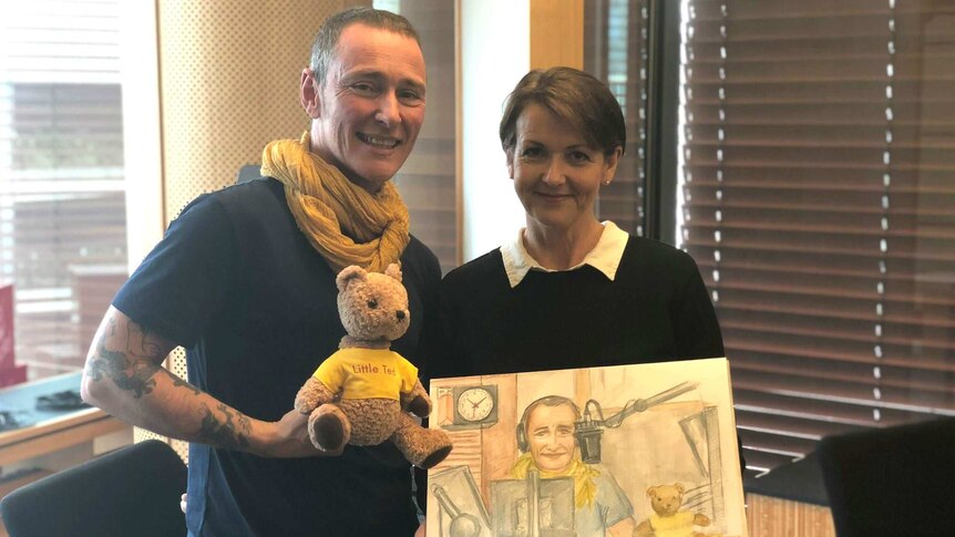 A man and woman and teddy bear with a drawing of the man