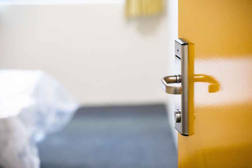 A yellow door with a handle which requires a key card to open.