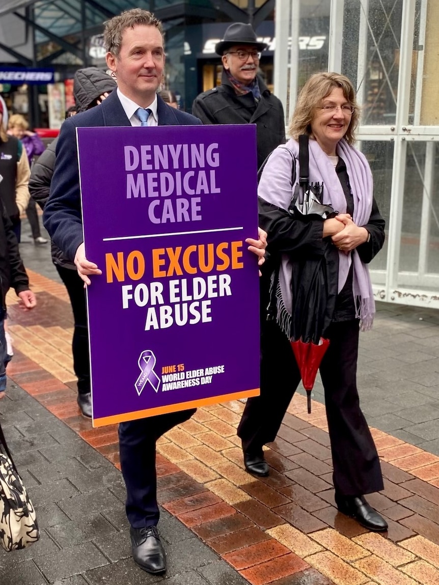 A man walks holding a sign with others.