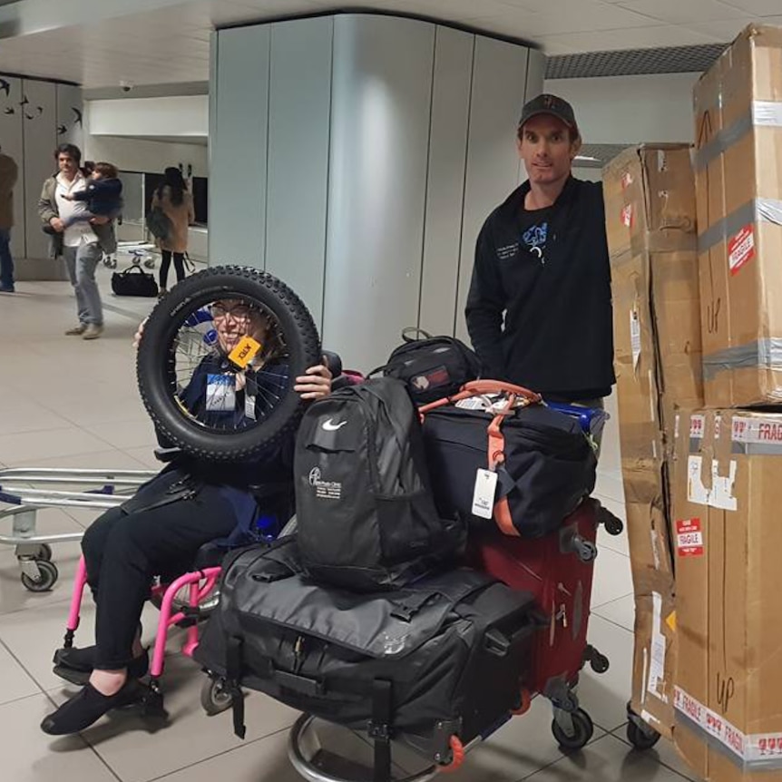 Johanna and her team wait at an airport with a trolley full of luggage.