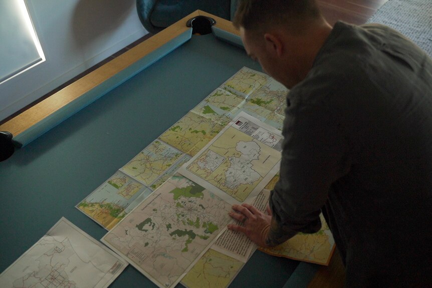 A man leans over a table looking at a map
