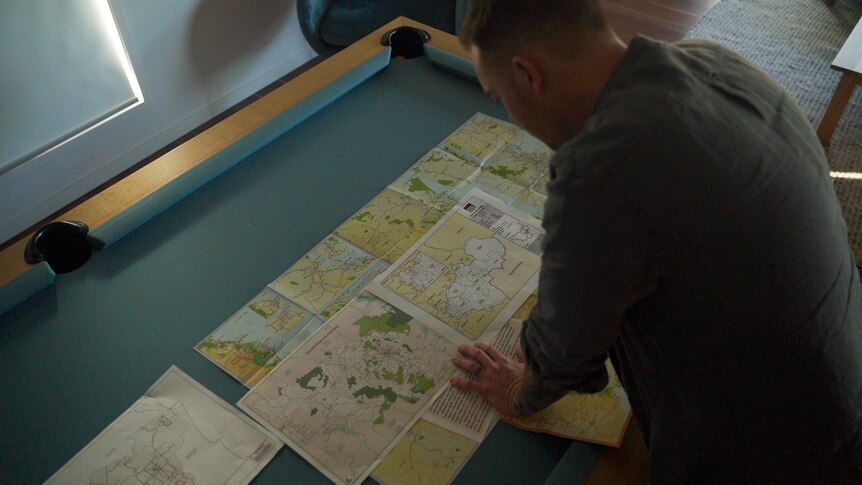 A man leans over a table looking at a map