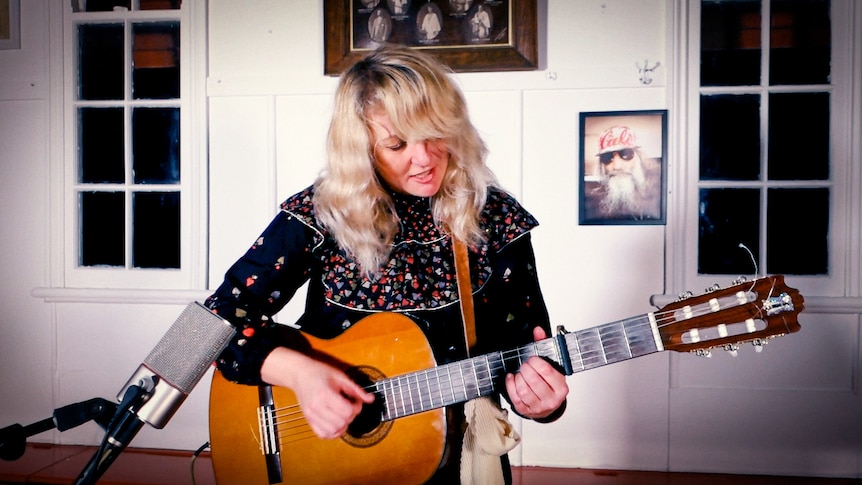 An image of Jackie singing with guitar
