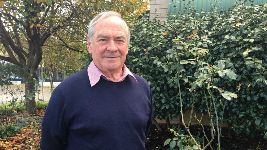 A man stands in front of rose bushes