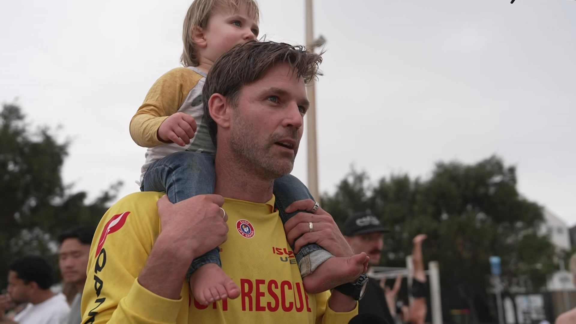 Um salva-vidas fala com um bebê no ombro. 