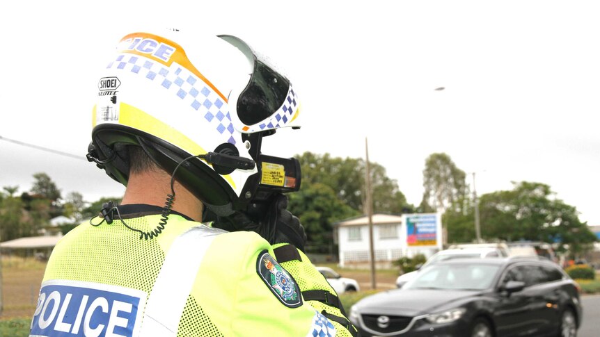 A police officer uses his speed gun at the roadside.