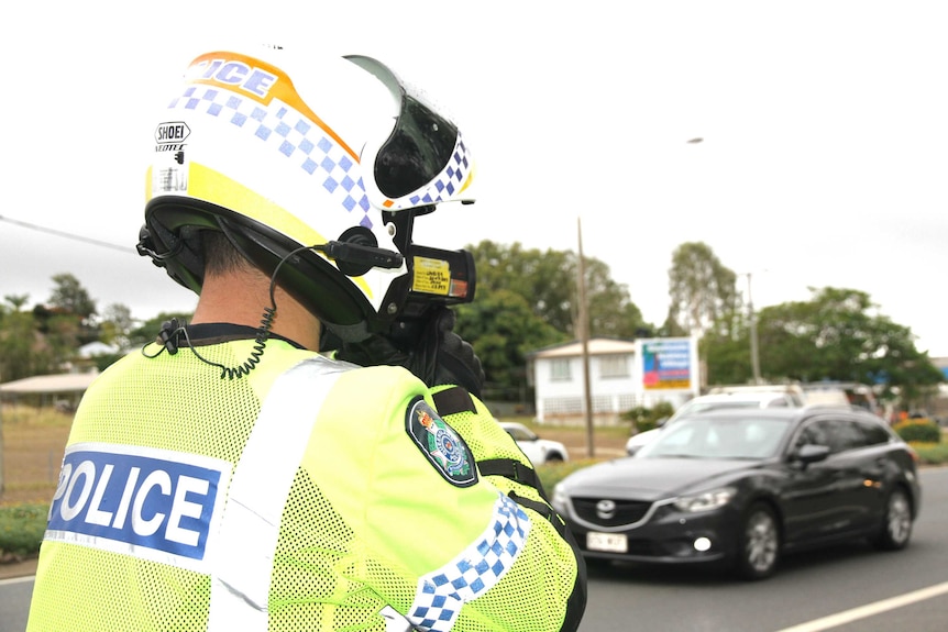 A police officer uses his speed gun at the roadside.