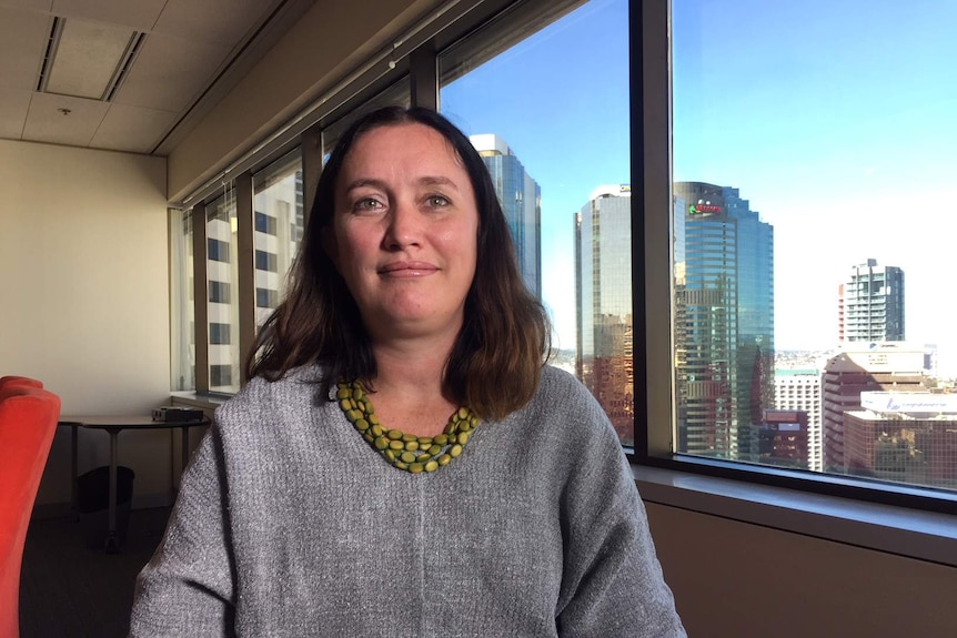 QNADA chief executive Rebecca Lang stands by her office window in Brisbane's CBD.