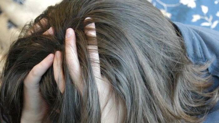 A young woman rests her head in her hands in a depressed pose