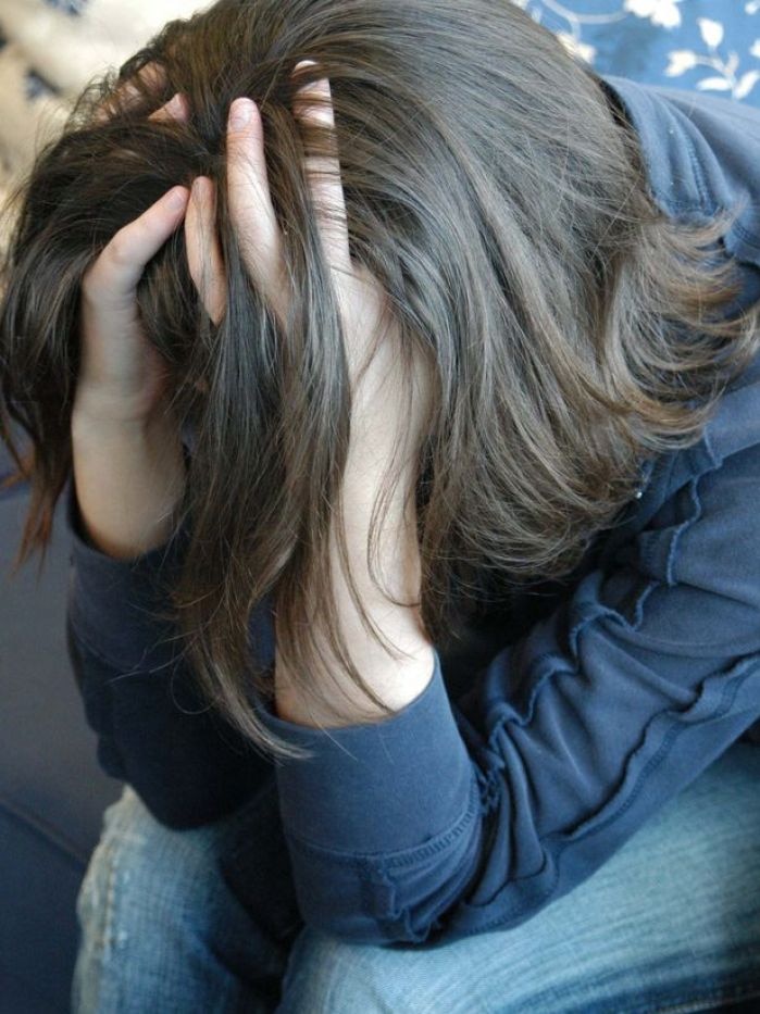 A young woman rests her head in her hands in a depressed pose