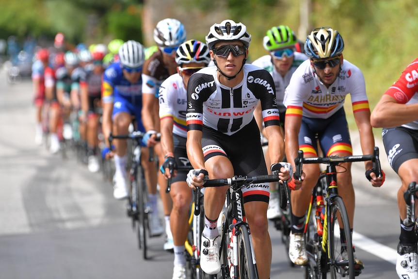 Jai Hindley leads a large group of riders wearing black and white kit