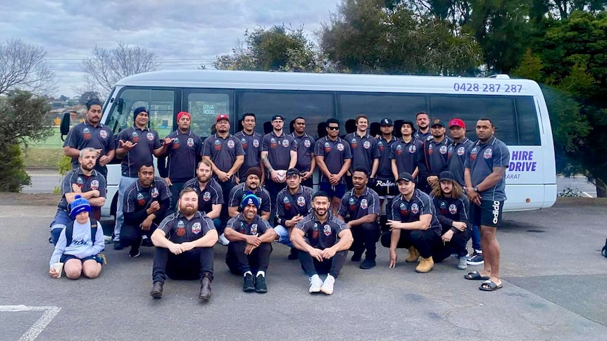 A group of players in navy blue jumpers standing in front of a bus