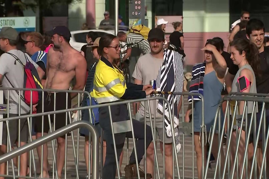 A woman in high-vis  manning a barrier at Coogee in Sydney.