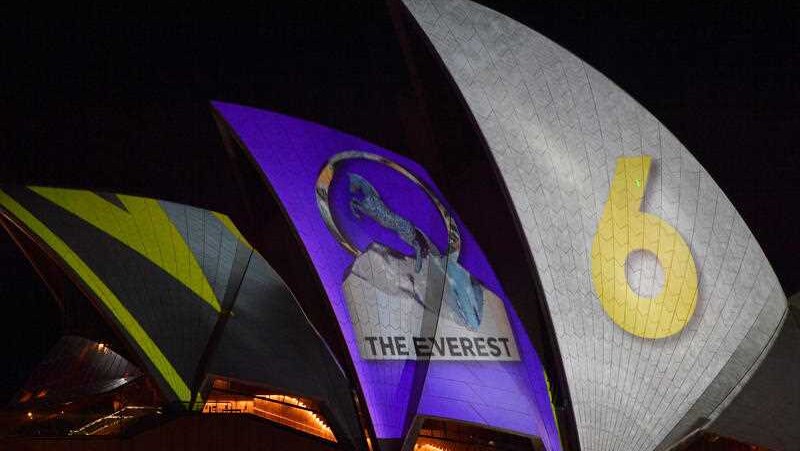The sails of the Opera House with racing imagery projected on.