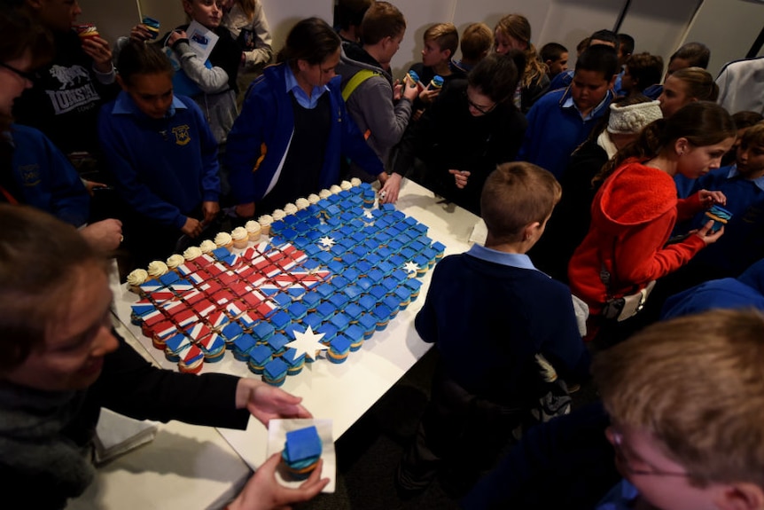 School kids surround a large Australian flag cake