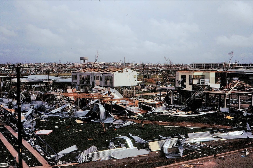 A few houses remain standing amid a huge area full of wreckage.