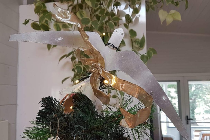 A metal bird mounted atop a Christmas tree.