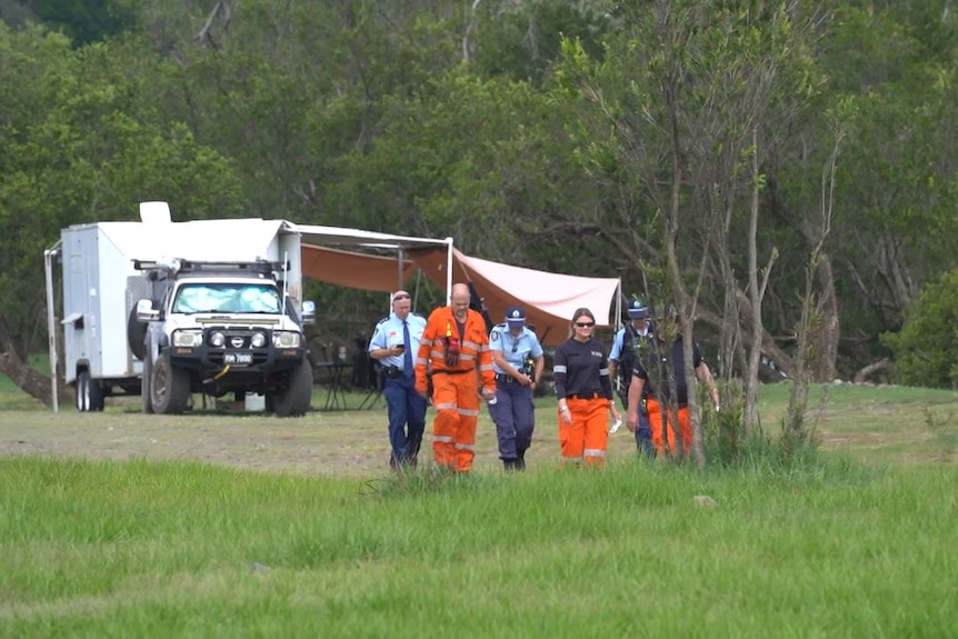 A group of seven SES and police walk toward the camera
