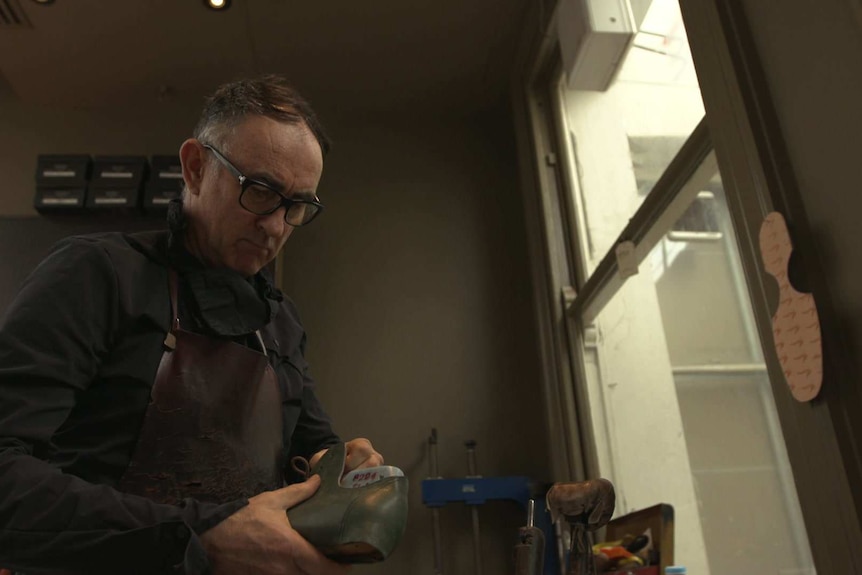 Shoemaker Andrew McDonald in his workshop holding a partly finished shoes