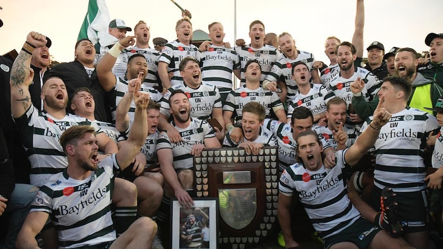 Warringah Rats' Sam Ward holds photo of his brother after Shute Shield win