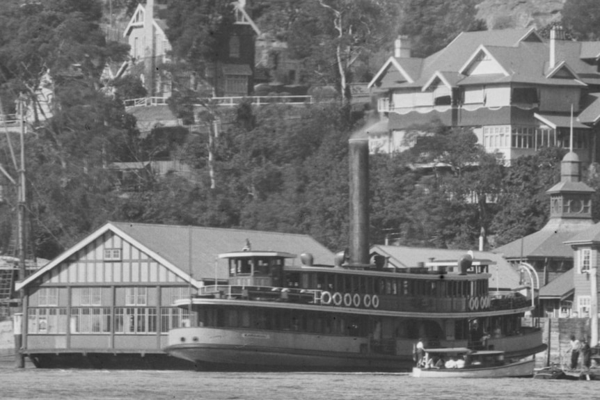 A black and white image of a large ship docked at a ferry terminal