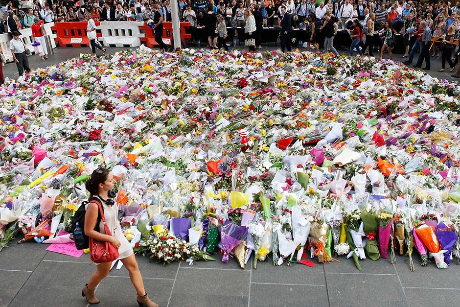Woman walks past floral tribute in Sydney CBD