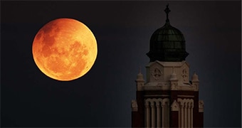 Rust coloured moon near church in Melbourne